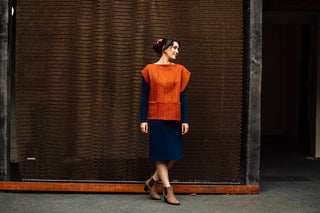 Photo of model wearing stylish wool outfit from the Salamanca Wool Shop. The model is standing in front of a rusted chainlink sculpture in Tasmania Australia. 